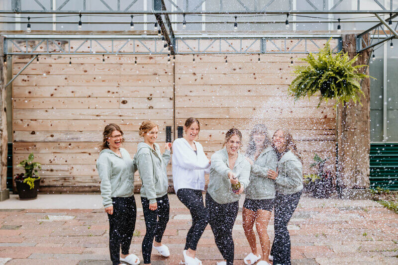 Bride and bridesmaids celebratory champagne opening