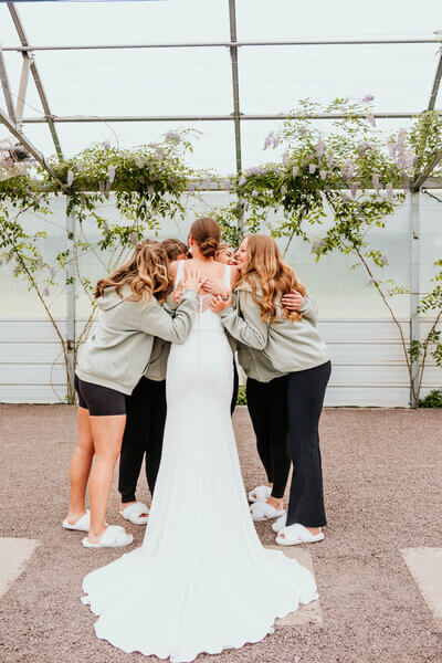 Bride and bridesmaids hugging in a greenhouse wedding venue in Wisconsin