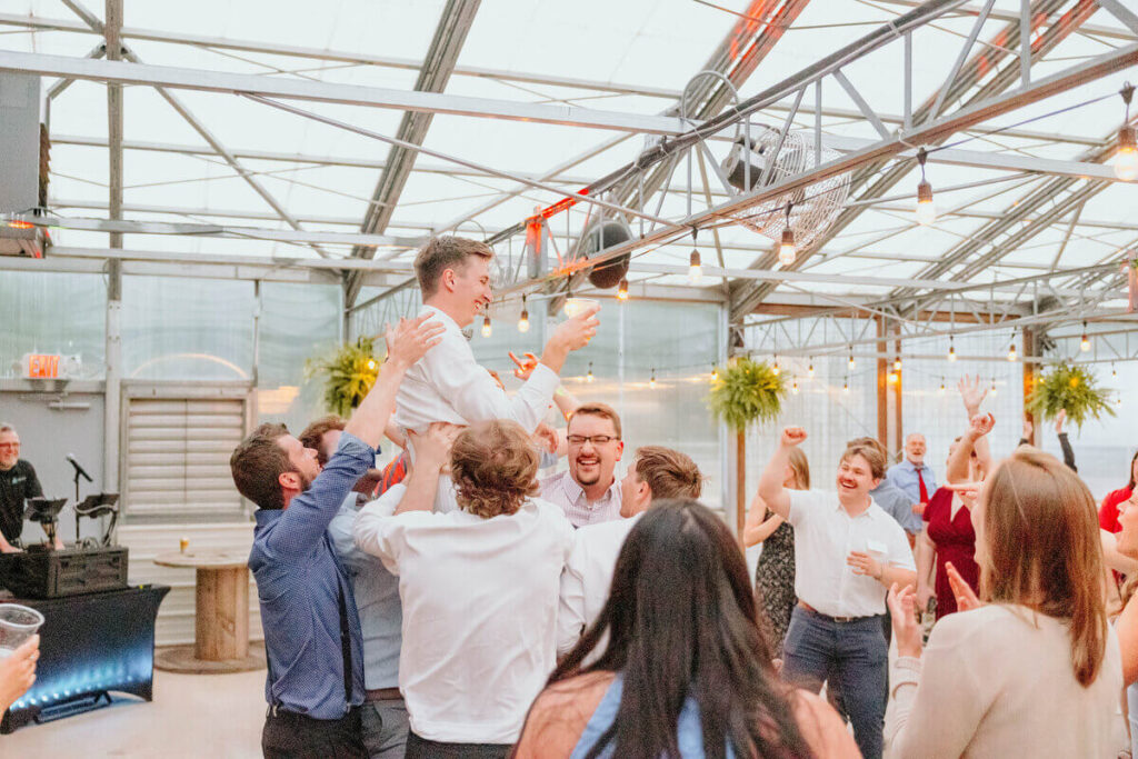 Wedding guests lifting up the groom
